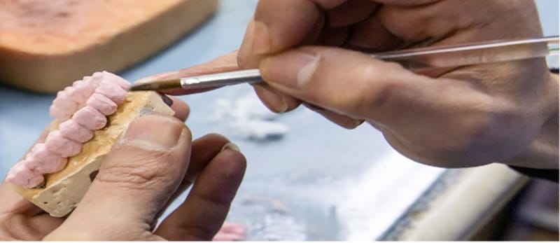 Teknik dentar duke modeluar një protezë në laboratorin e klinikës
